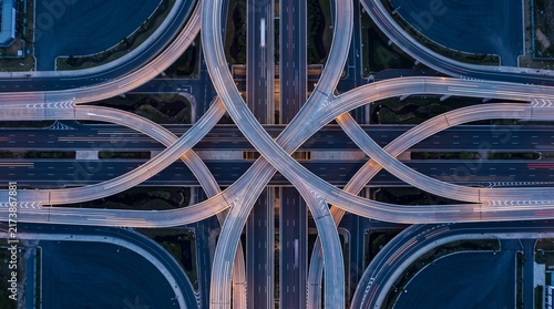 Aerial top view of modern highway interchange junction at dusk with traffic light trails