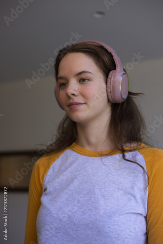 Obraz na płótnie Female wearing pink over-ear headphones and yellow raglan, looking right at home