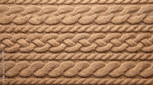 Close-up textile texture with braided cable knit patterns in warm neutral tones