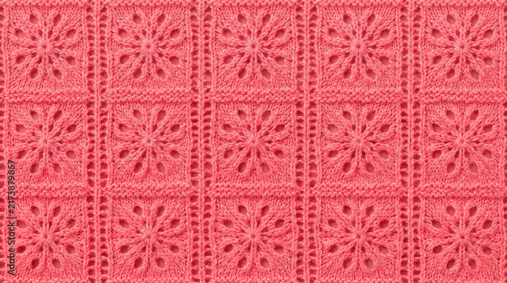 Coral knitted fabric with floral pattern in even rows showing textile texture and detail