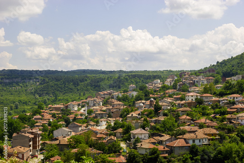 Photography A panoramic view of the historic town of Veliko Tarnovo, Bulgaria, nestled on a hillside under a cloudy sky