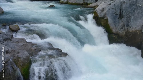 Scenic view of rushing turquoise river water flowing rapidly over grey mountain rocks in nature