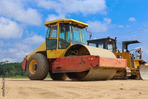 Foto road roller with yellow color, on construction site and sky background