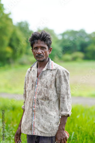 Foto a hard-working Indian farmer standing outdoors in a field wearing a mud-stained shirt after a long day of labor