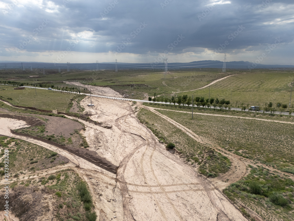 Naklejka premium Muddy dry riverbed and dirt road after heavy rain on the grassland plains