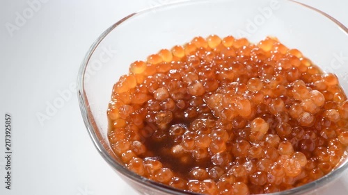 Fresh salmon roe in soy sauce marinade showcased in a glass bowl with glossy texture