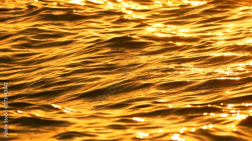 Sunset water waves reflecting golden light on the rippling surface of the sea during a calm evening