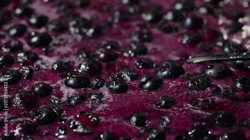Fresh blueberries and rich purple juice boil and bubble while making homemade berry jam.