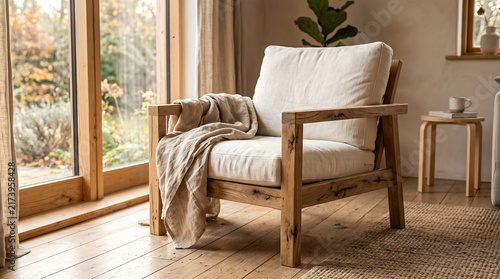 Natural oak furniture and soft textiles create a welcoming seating corner beside a bright window. Realistic home lifestyle photography with warm sunlight