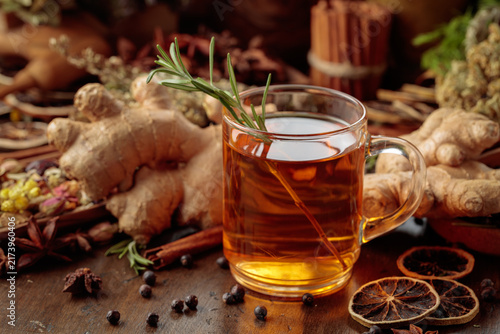 Warming herbal tea with fresh ginger, dried orange slices, juniper berries and spices served in a glass mug.