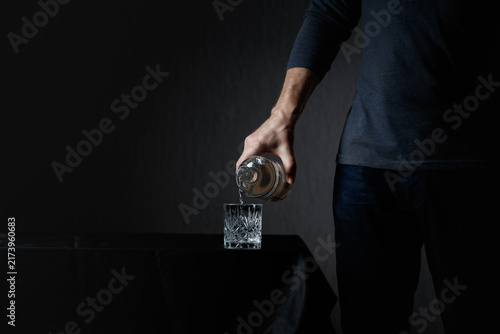 фотографія Man pouring strong alcoholic drink in glass.