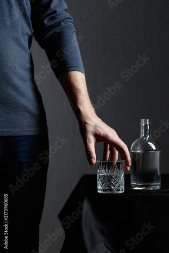 Obraz na plátně Man pouring strong alcoholic drink in glass.