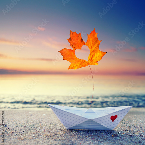 Handmade Paper Boat with Colorful Autumn Leaf on a Baltic Sea Beach at Sunset