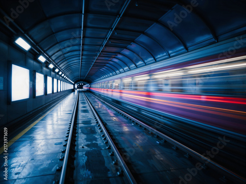 Subway train speeding through a blue-toned tunnel station