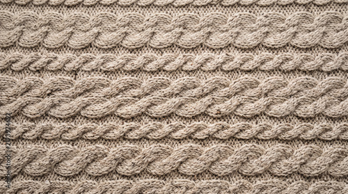 Detailed textured knitted wool fabric with intricate cable patterns in warm beige tones a cozy textile background