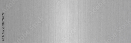 Brushed aluminum texture background with vertical grain. Silver metal surface with light reflection. Industrial stainless steel plate for tech design. Polished metallic backdrop for web.