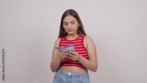 Happy Indian Teenage Girl Counting 100 Indian Rupee Notes and Smiling
