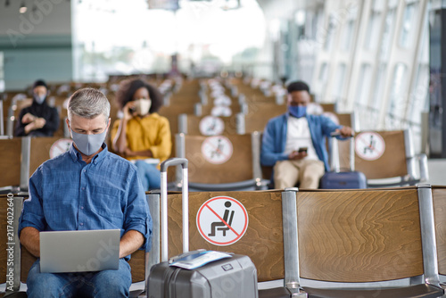 Obraz na płótnie Travelers maintain physical distance while waiting for flights, adhering to safe