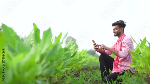 young indian farmer using smartphone at green turmeric agriculture field