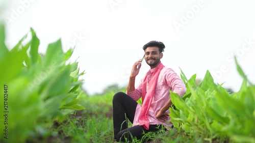 young indian farmer talking on mobile phone at green turmeric agriculture field