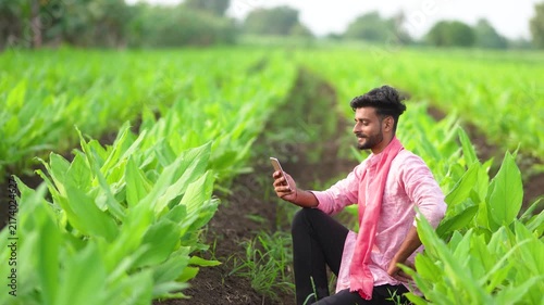 young indian farmer using smartphone at green turmeric agriculture field