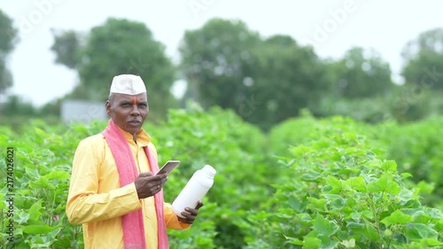 Senior Indian farmer using smartphone at cotton agriculture field 