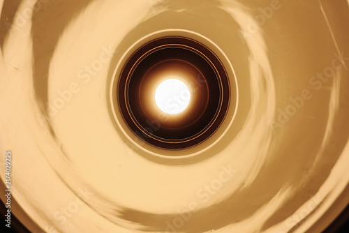 Fotografie Warm ceiling light inside circular recessed fixture with concentric metal rings and amber glow
