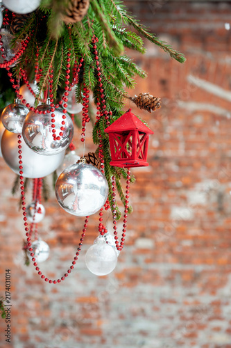 Rustic brick backdrop with christmas ornaments hang from spruce branches