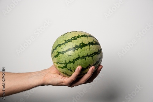 Canvastavla Watermelon held in hand against light background