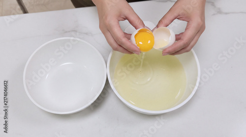 Separating egg yolk from white over ceramic bowls top view