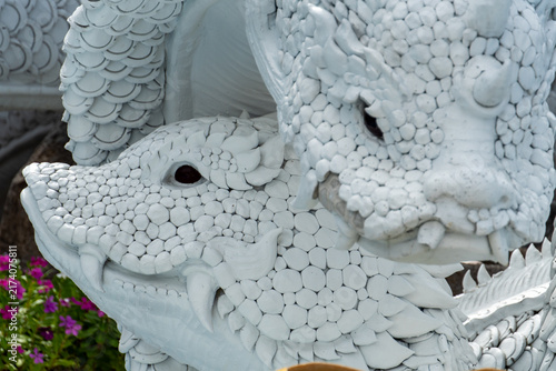 Canvas Print Intricate white dragon statues with detailed scales and sharp teeth in sunlight