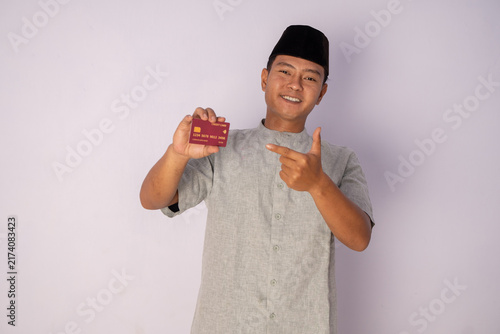 Young Man with a Proud Smile Holding a Membership Card Against a Light Background
