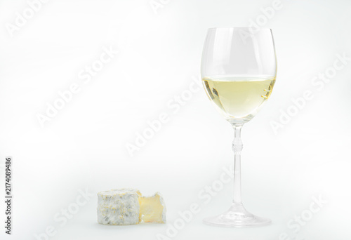 Traditional French goat cheese Crottin de Chavignol with a glass of white wine on a white background.