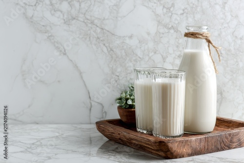 Fresh milk in glass bottles and drinking glasses on wooden tray, healthy dairy drink and natural breakfast nutrition concept.