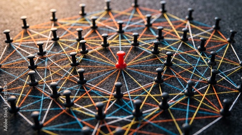 Vibrant red pushpin stands out among many black pins connected by colorful thin threads in a complex geometric web formation