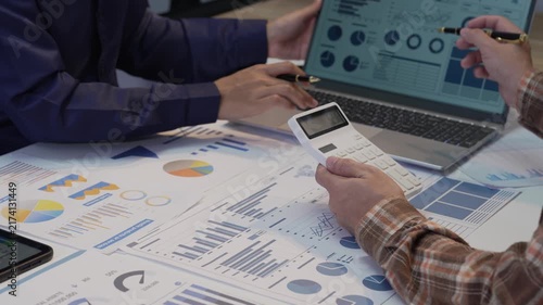 Business colleagues working together analyzing financial graphs on digital tablet and using calculator in office