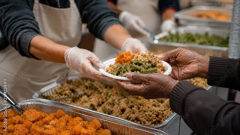Obraz premium Volunteer wearing a white apron and plastic gloves serving a plate of food to a person in need at a community soup kitchen