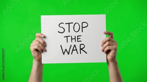 Hands holding a banner sign with the text stop the war on a green screen chroma key background
