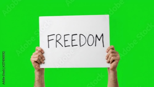 Hands holding a banner sign with the text freedom on a green screen chroma key background