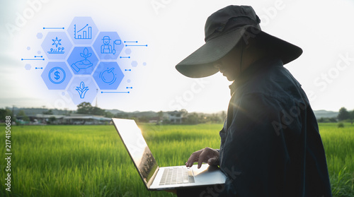Farmer using laptop in green field with digital agriculture icons representing technology and innovation