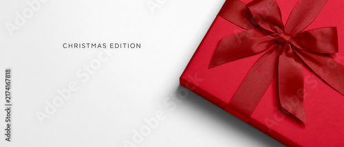 Red Christmas gift box with ribbon bow on white background. Minimalist holiday present banner