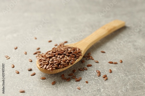 Фотография Flax seeds in spoon on grey table, closeup