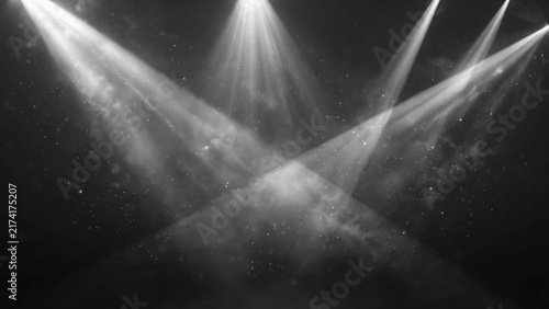 Bright spotlights cut through smoky darkness, illuminating shimmering particles