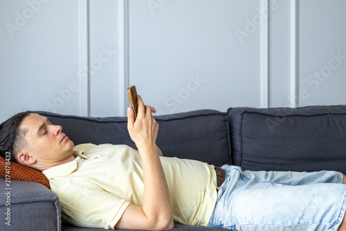 Photography Middle aged man lies alone on couch checking phone while relaxing at home during quiet afternoon