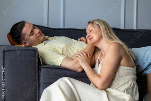 Obraz na plátně Woman nestles against man's arm with eyes closed while he smiles tenderly at her