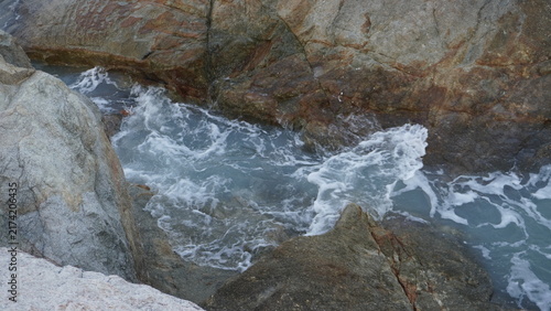 Obraz na płótnie Frothy white ocean waves surging through a narrow channel between wet granite rocks