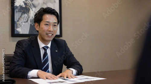 会議室で笑顔で商談するスーツ姿の日本人男性