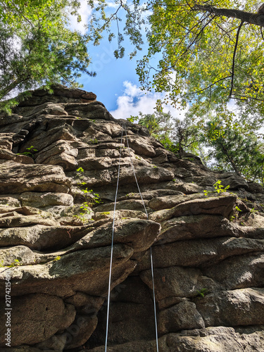 Фотография A group of people climb a rocky wall in a forest area