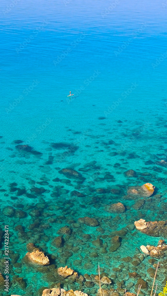 Fototapeta premium Persona su stand up paddle nel mare cristallino e turchese di Tropea