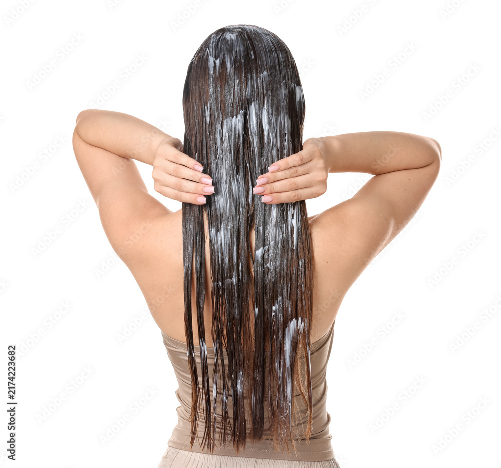 Obraz premium Woman applying mask onto her hair against white background, back view